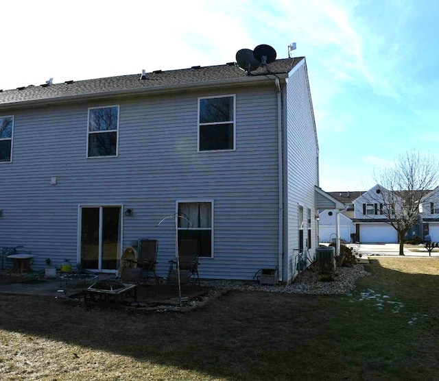 back of house with a garage, central AC, a lawn, and a patio area