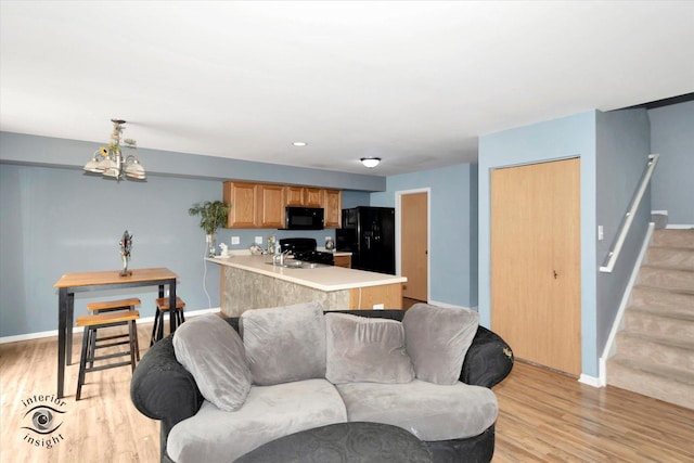 living area featuring stairway, baseboards, and light wood-style floors