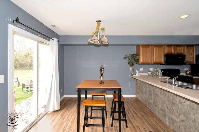dining room featuring a chandelier, light wood-style floors, visible vents, and baseboards