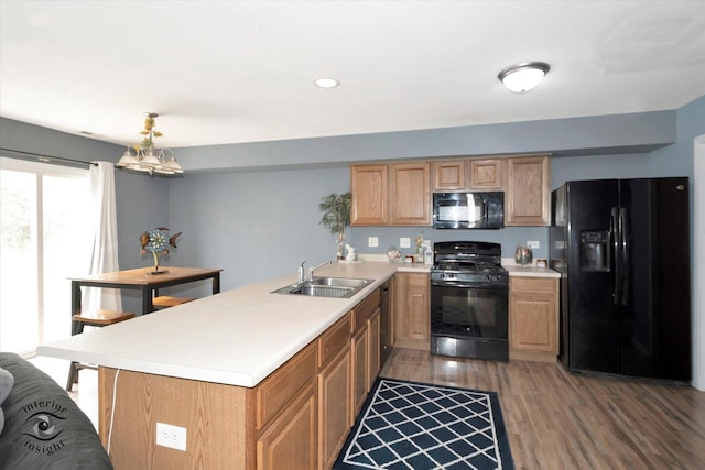 kitchen featuring a sink, black appliances, light wood finished floors, light countertops, and a peninsula