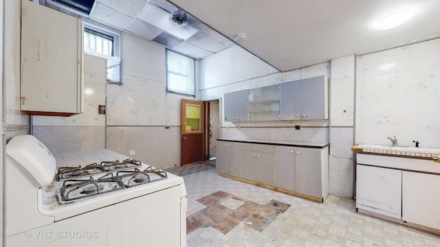 kitchen with gray cabinets, sink, and white gas stove