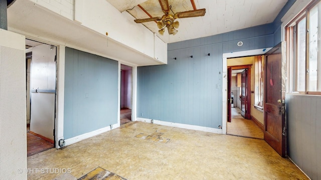 empty room featuring ceiling fan and wood walls