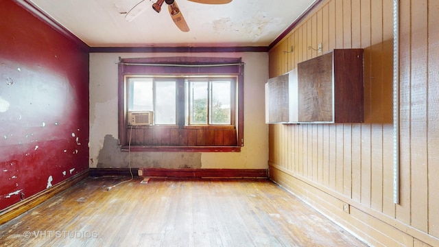 unfurnished room featuring cooling unit, ceiling fan, ornamental molding, and light hardwood / wood-style flooring