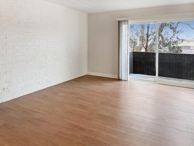 empty room featuring brick wall and wood-type flooring