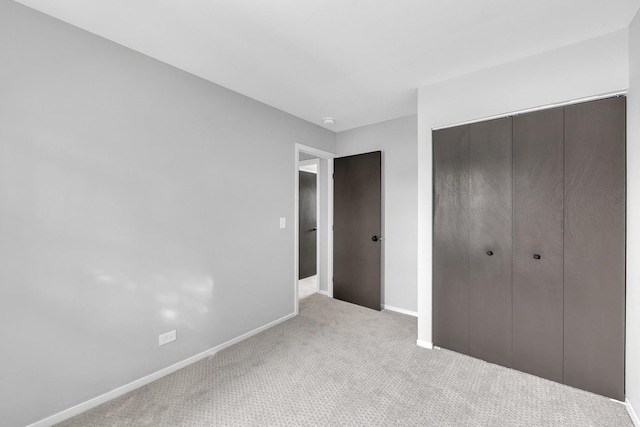 unfurnished bedroom with light colored carpet and a closet