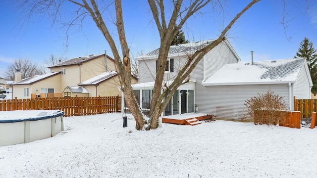 snow covered rear of property featuring a pool side deck