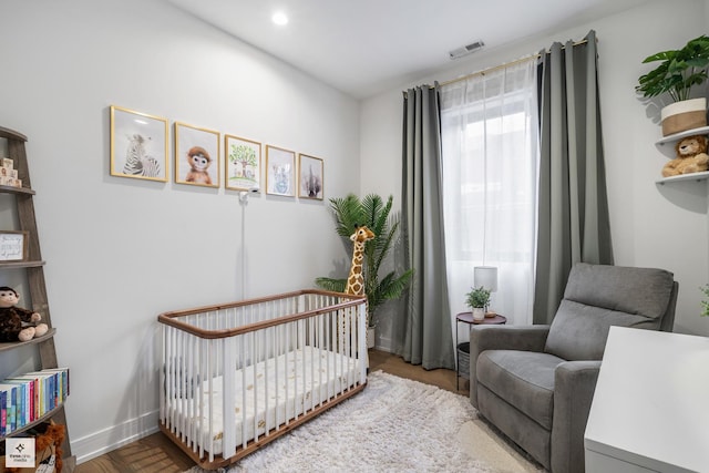 bedroom featuring a nursery area and hardwood / wood-style floors