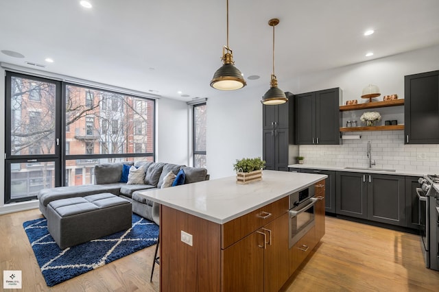 kitchen with decorative light fixtures, sink, decorative backsplash, a center island, and light stone countertops