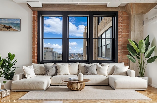 living area featuring brick wall, baseboards, and parquet flooring