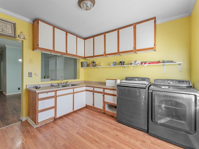 laundry area featuring ornamental molding, sink, independent washer and dryer, and light wood-type flooring