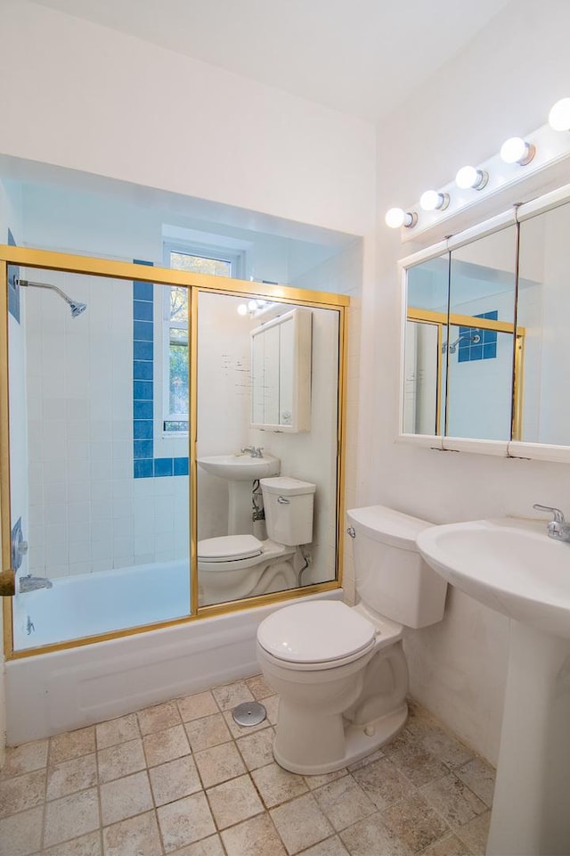 bathroom featuring toilet and shower / bath combination with glass door