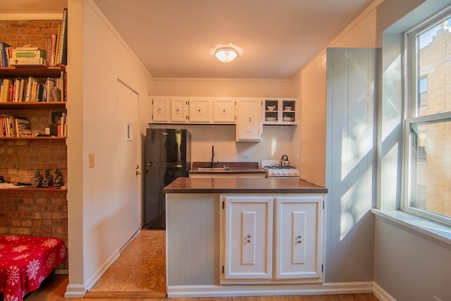 kitchen with black refrigerator, sink, white cabinets, white range oven, and crown molding