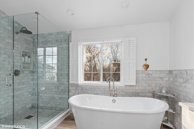 bathroom featuring hardwood / wood-style floors, plus walk in shower, and tile walls