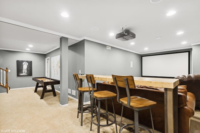 home theater room featuring ornamental molding, light carpet, and bar area