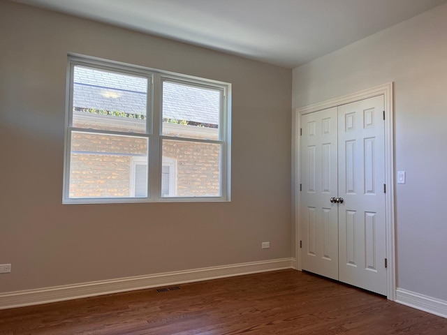 unfurnished bedroom featuring dark wood-type flooring and a closet