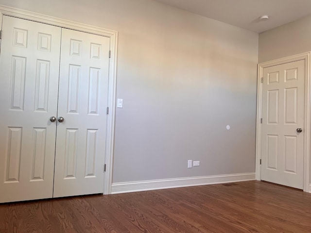 unfurnished bedroom with dark hardwood / wood-style flooring and a closet