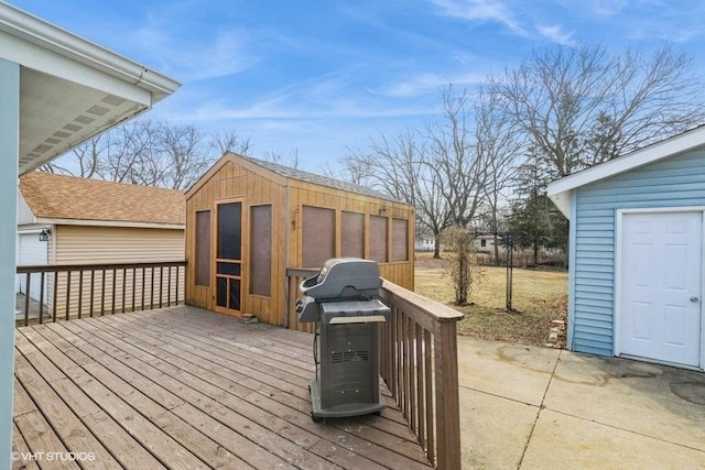 wooden deck featuring a storage shed and a grill