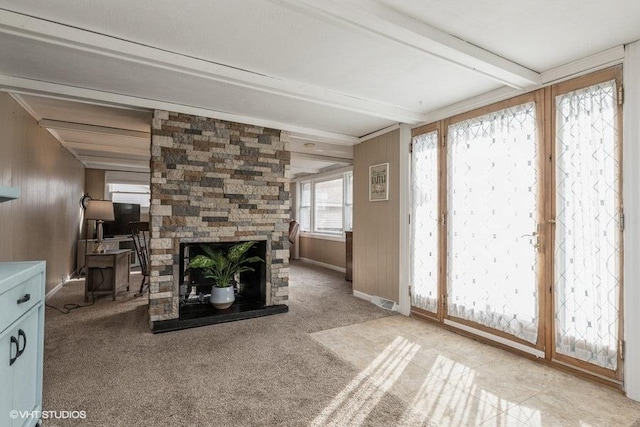 unfurnished living room featuring light carpet, a fireplace, and beam ceiling