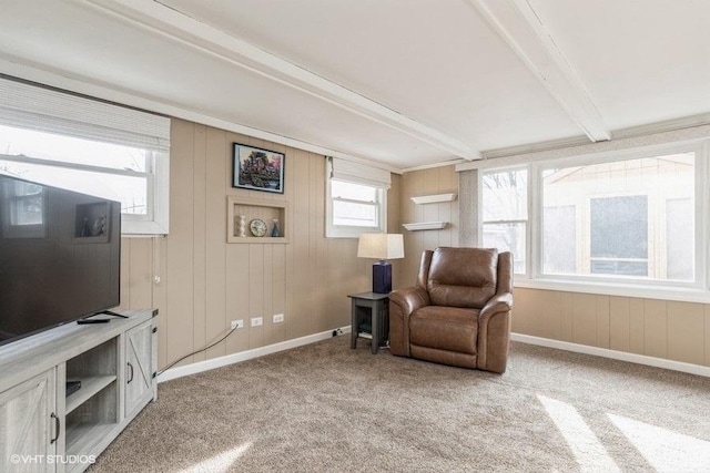 living area featuring beamed ceiling and carpet