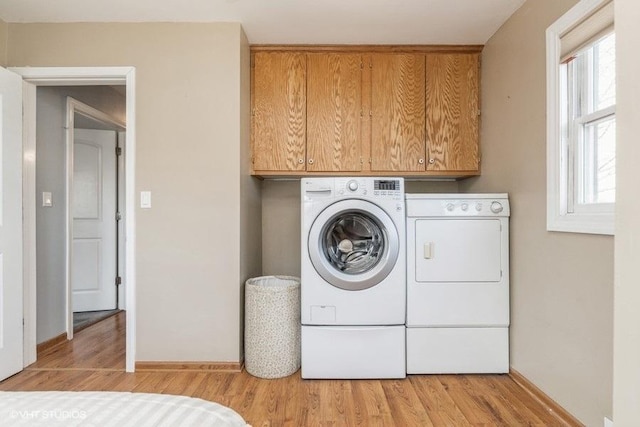 laundry area with cabinets, independent washer and dryer, and light hardwood / wood-style flooring