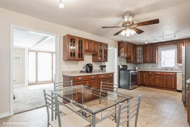 kitchen featuring light tile patterned flooring, sink, ceiling fan, stainless steel appliances, and backsplash