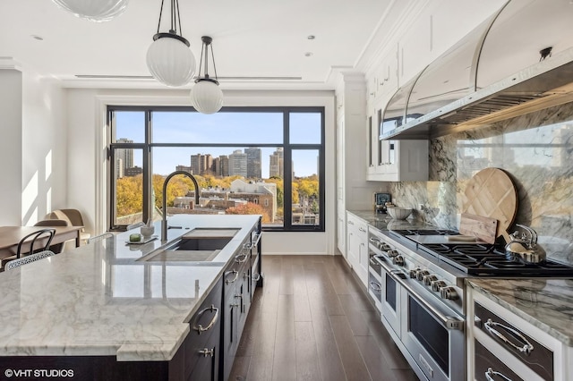 kitchen with ventilation hood, range with two ovens, decorative backsplash, white cabinets, and a sink