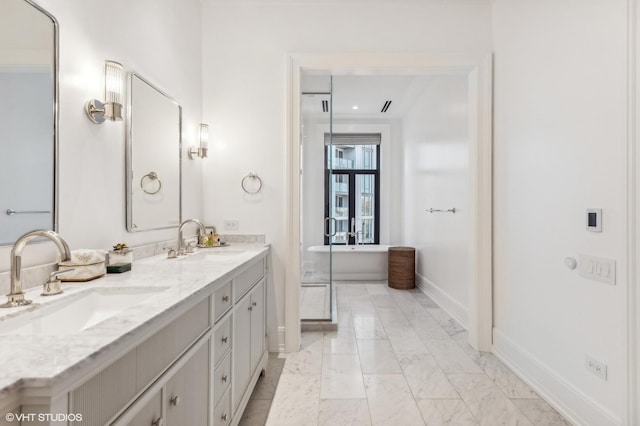 bathroom with double vanity, a freestanding tub, marble finish floor, and a sink