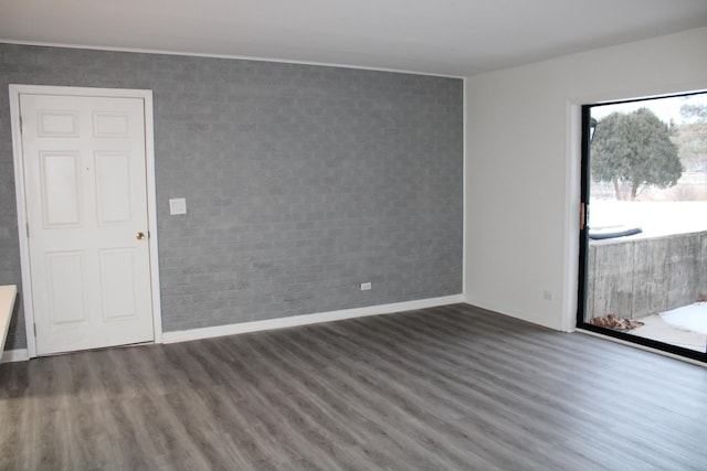 spare room with dark wood-type flooring and brick wall