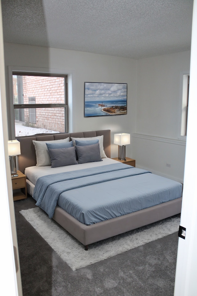 bedroom with a textured ceiling and dark carpet