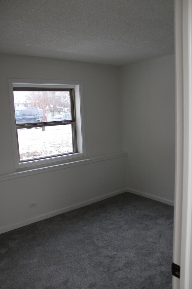 spare room with dark colored carpet and a textured ceiling