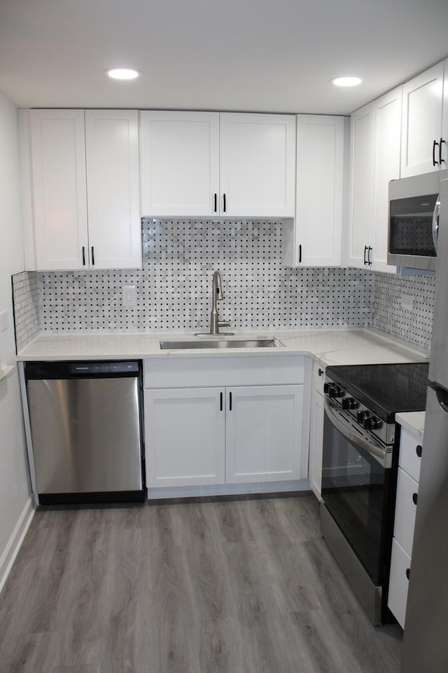 kitchen featuring stainless steel appliances, hardwood / wood-style flooring, sink, and white cabinets