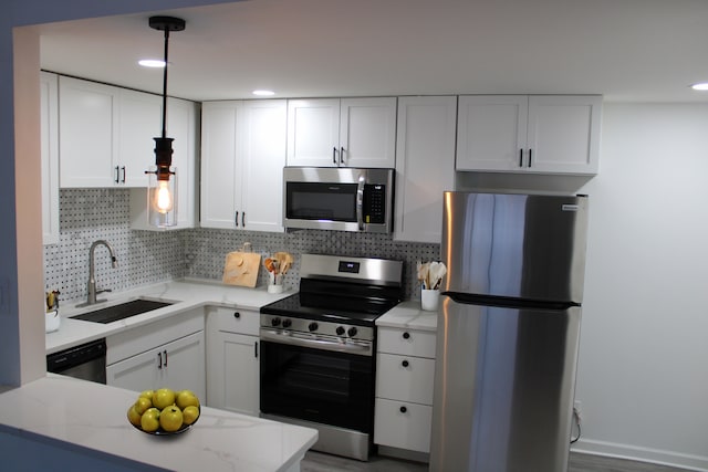 kitchen featuring appliances with stainless steel finishes, sink, white cabinets, decorative backsplash, and hanging light fixtures