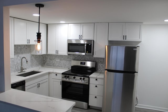 kitchen with appliances with stainless steel finishes, decorative light fixtures, white cabinetry, sink, and backsplash