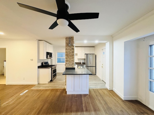 kitchen featuring ornate columns, white cabinets, ceiling fan, stainless steel appliances, and light wood-type flooring