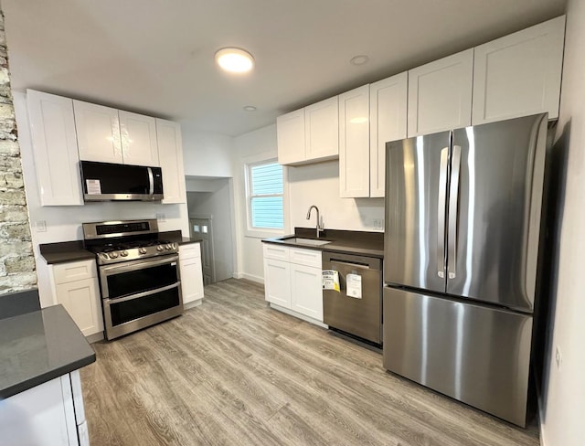 kitchen featuring white cabinetry, appliances with stainless steel finishes, sink, and light wood-type flooring