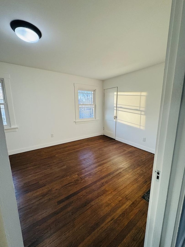 unfurnished room featuring a wealth of natural light and dark wood-type flooring