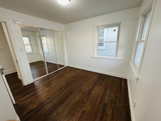 unfurnished bedroom with dark hardwood / wood-style flooring and a closet