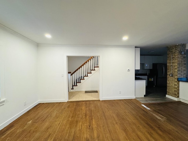 unfurnished living room with crown molding and hardwood / wood-style floors