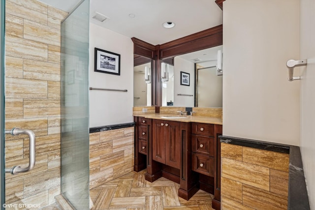 bathroom featuring an enclosed shower, vanity, parquet flooring, and tile walls