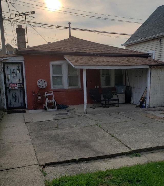 back house at dusk featuring a patio area