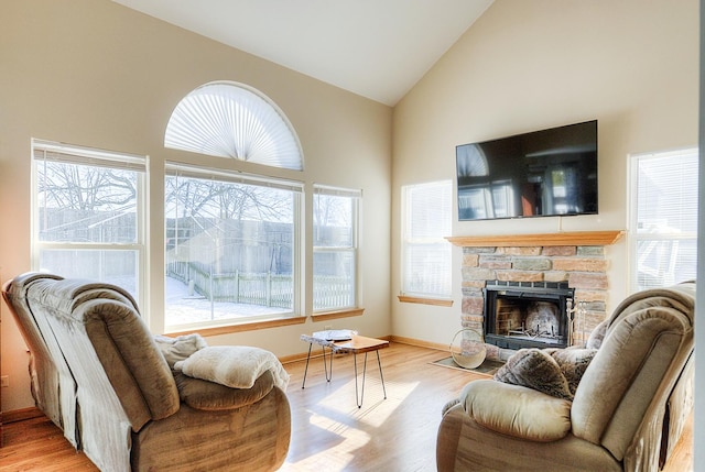 living room featuring high vaulted ceiling, a fireplace, and light hardwood / wood-style floors