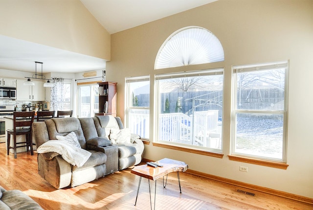 living room with high vaulted ceiling and light hardwood / wood-style floors