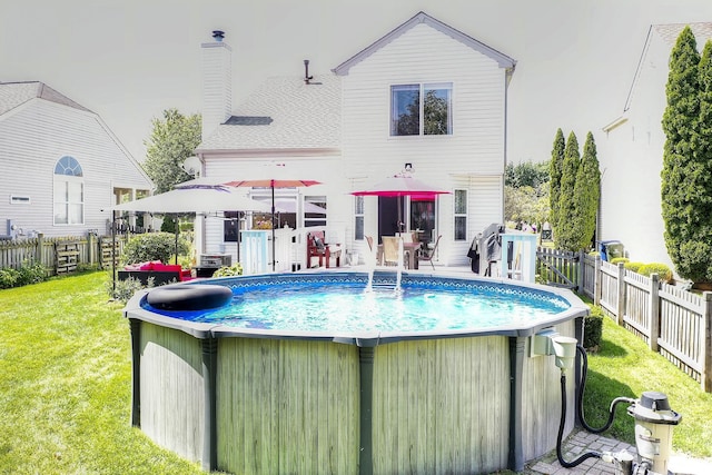 back of property with a fenced in pool and a lawn