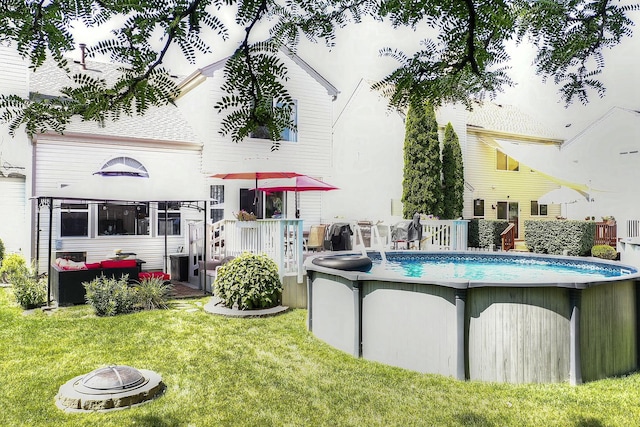 rear view of house with a swimming pool side deck and a lawn