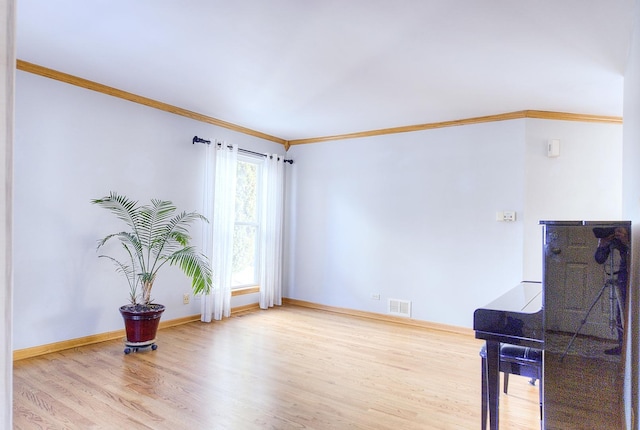 spare room featuring ornamental molding and light hardwood / wood-style flooring