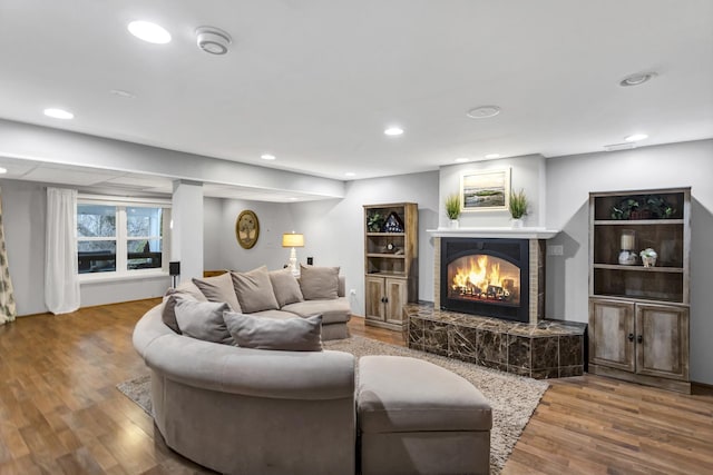 living room featuring a glass covered fireplace, recessed lighting, and wood finished floors