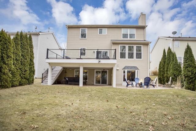 back of house with a chimney, a patio, a lawn, and stairs