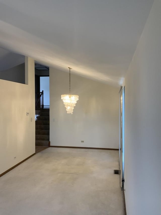 carpeted spare room featuring lofted ceiling and a chandelier