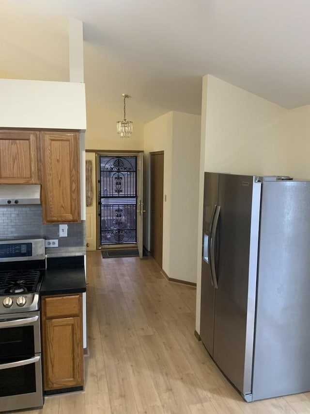 kitchen featuring hanging light fixtures, light wood-type flooring, stainless steel appliances, decorative backsplash, and exhaust hood