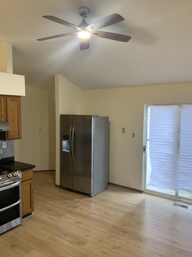 kitchen featuring backsplash, vaulted ceiling, stainless steel appliances, and light wood-type flooring